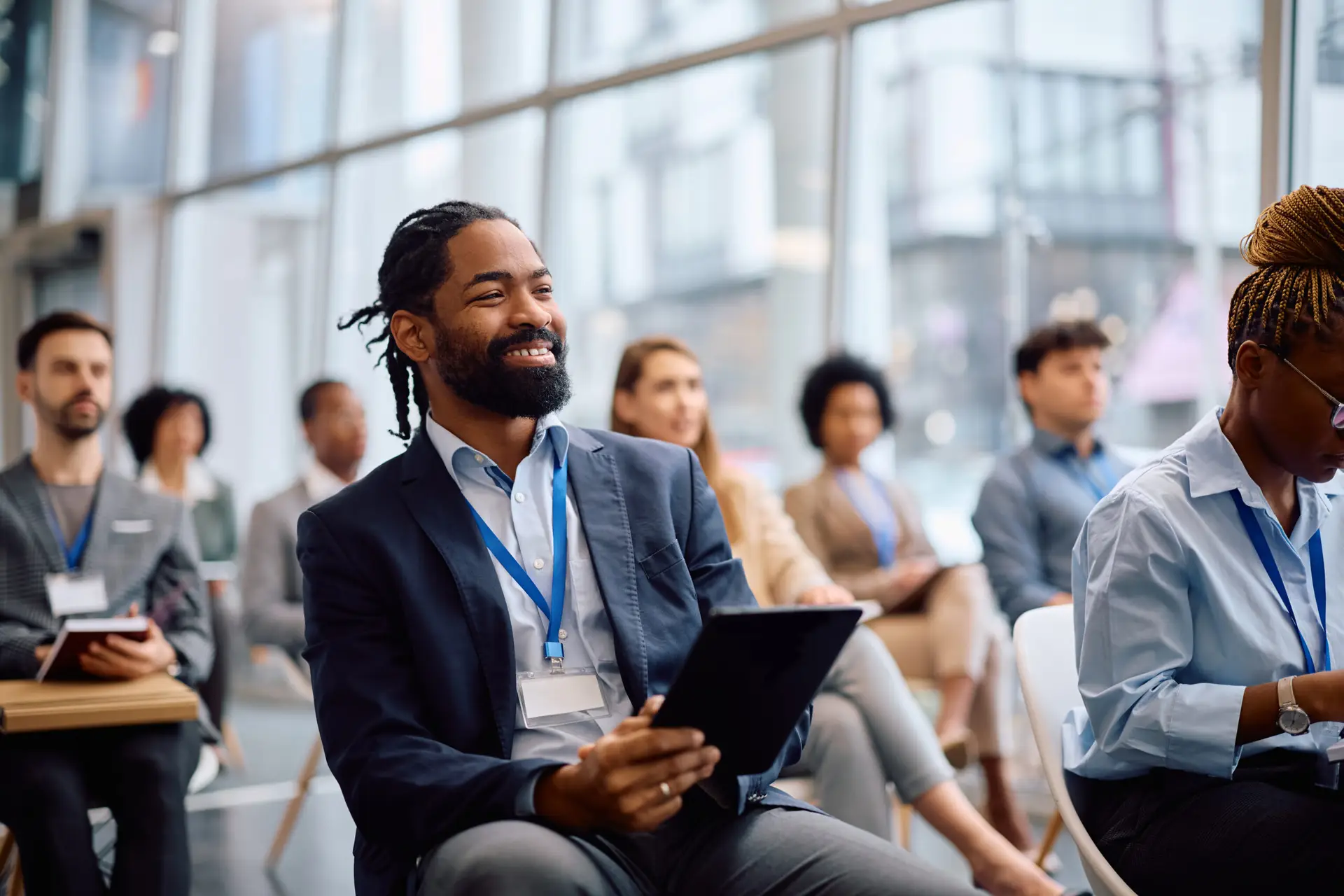 Professional smiling while holding a tablet at a conference